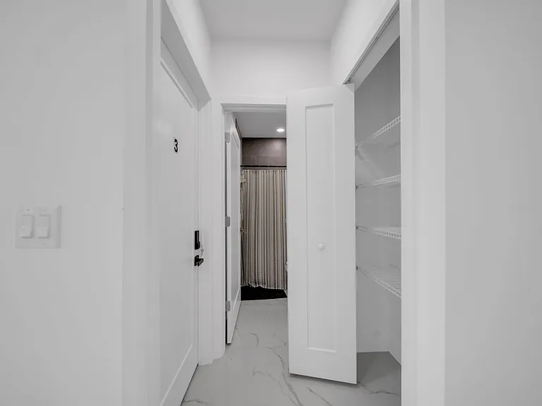 Hallway with built-in shelving/linen closet and direct access to a bathroom featuring tile finishes and a shower/tub.