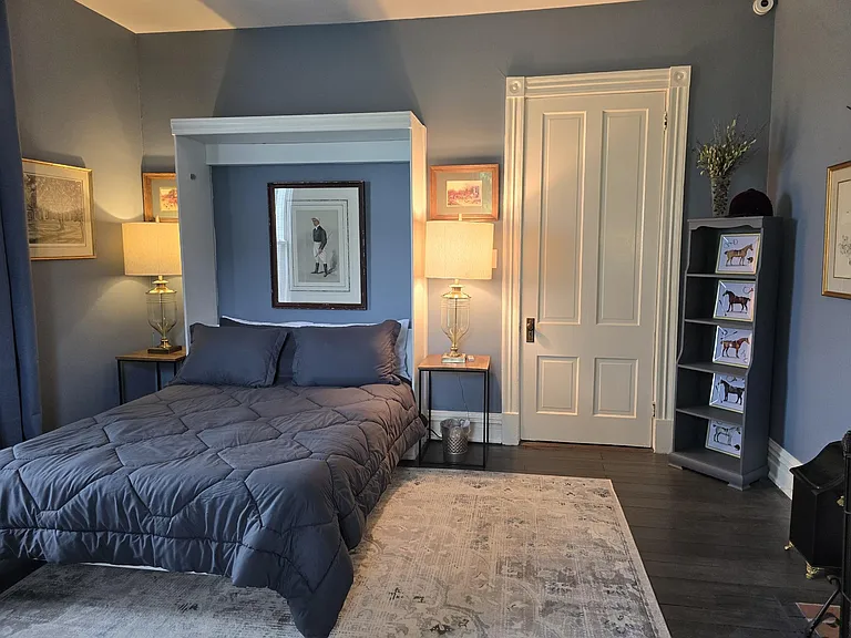View of bed with door closed; book case to right of door.