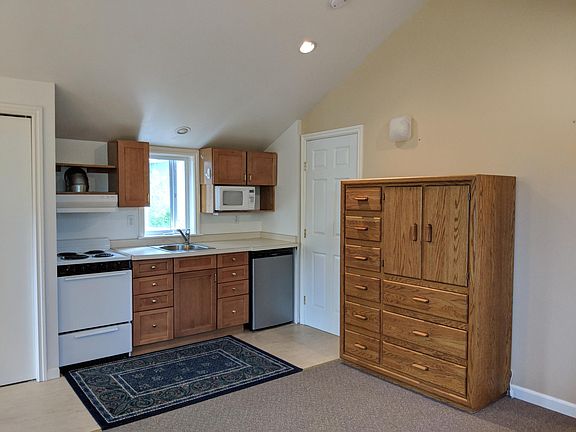 Complete kitchen with stove, microwave, refrigerator. Double closet on the left, storage unit on the right. Notice high cathedral ceilings.
