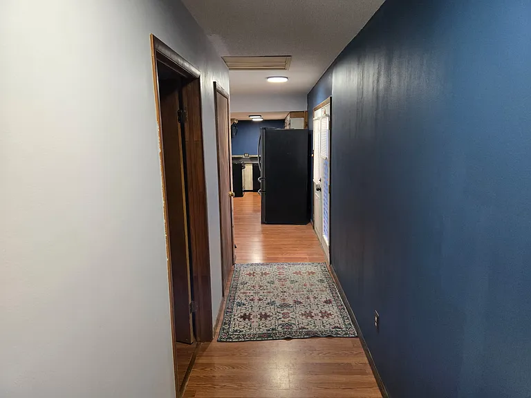 Hallway from the garage to the kitchen area. Bedroom 1 is the first door on the left and the next is a walk-in broom closet with access to the basement.