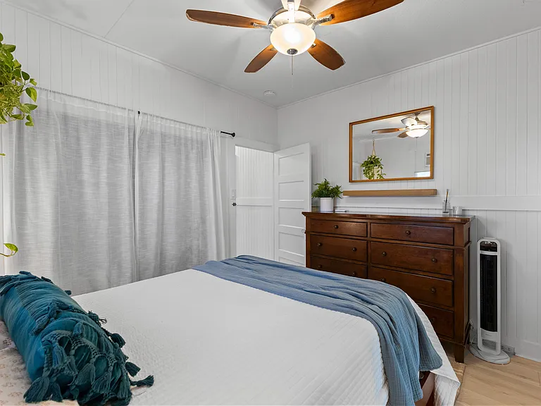Front bedroom with queen bed, side tables, dresser, AC, ceiling fan, window and large closet with built-in shelving. French doors open to enclosed lanai.