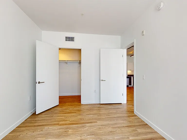 Spacious apartment bedroom with wood-style flooring.