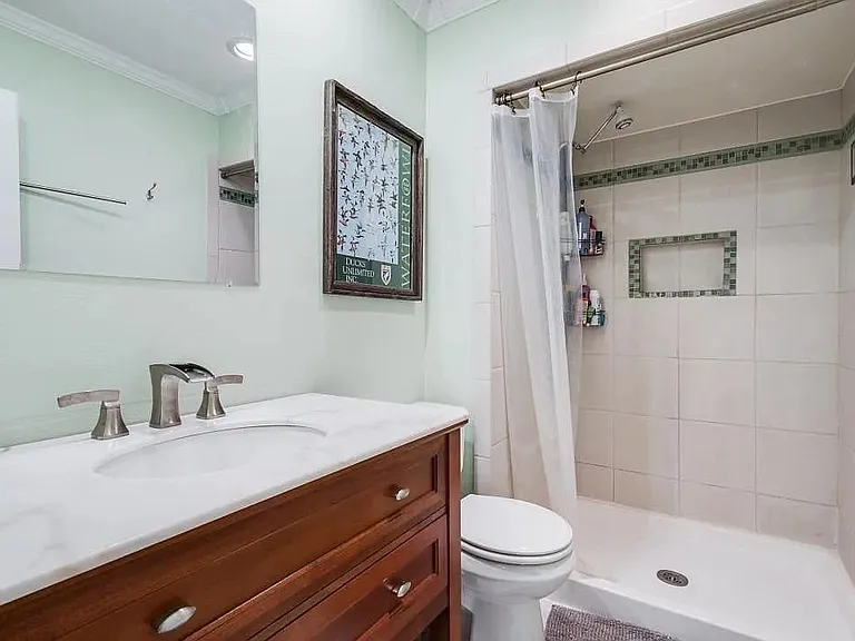 Bathroom featuring a wood-finish vanity with a white countertop, undermount sink, and brushed nickel fixtures