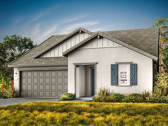 A quaint, single-story house with a gray exterior and a gabled roof sits amidst a lush, colorful gar