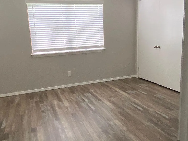 Larger than it looks master bedroom with ceiling fan, blinds and backyard view.