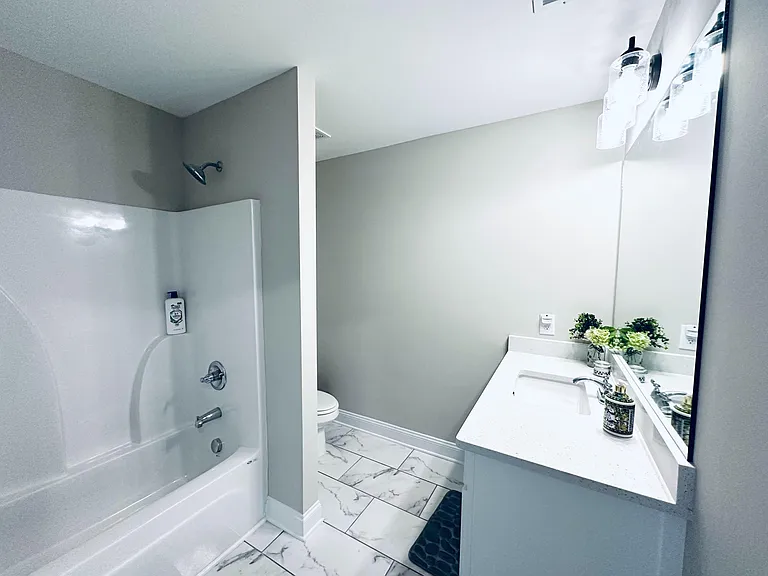 Full bath with tub/shower combo, wide vanity with mirror, and tile flooring for easy upkeep.