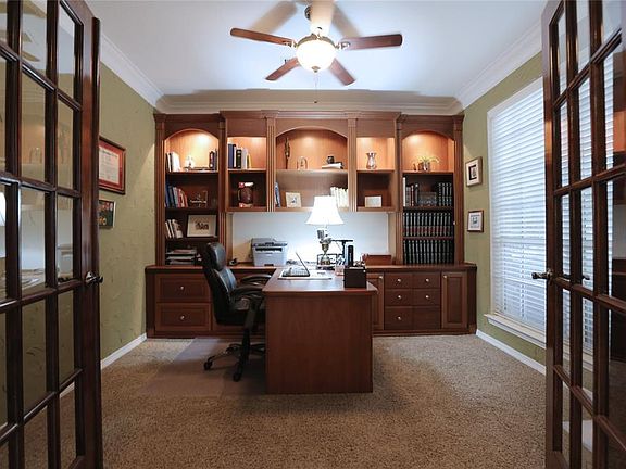 Custom mahogany cabinetry with accent lighting is the focal point of the study.