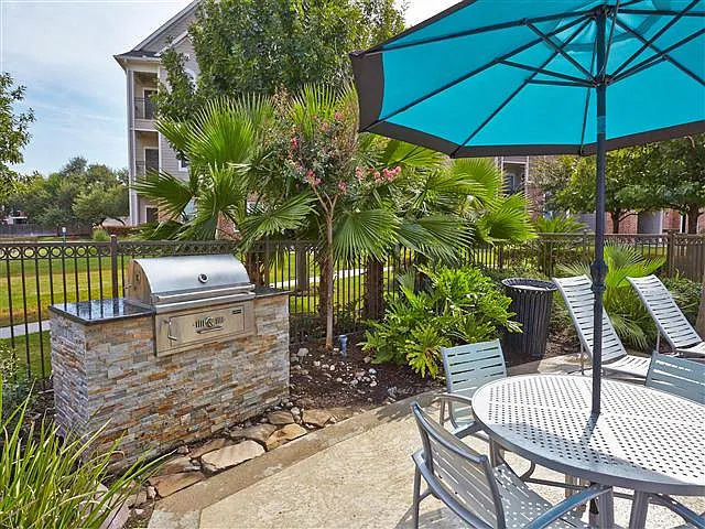 Outdoor poolside grill with umbrella covered table and seating