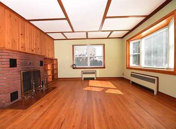 Large and bright living room with wood burning fireplace, hardwood floors and replacement windows.