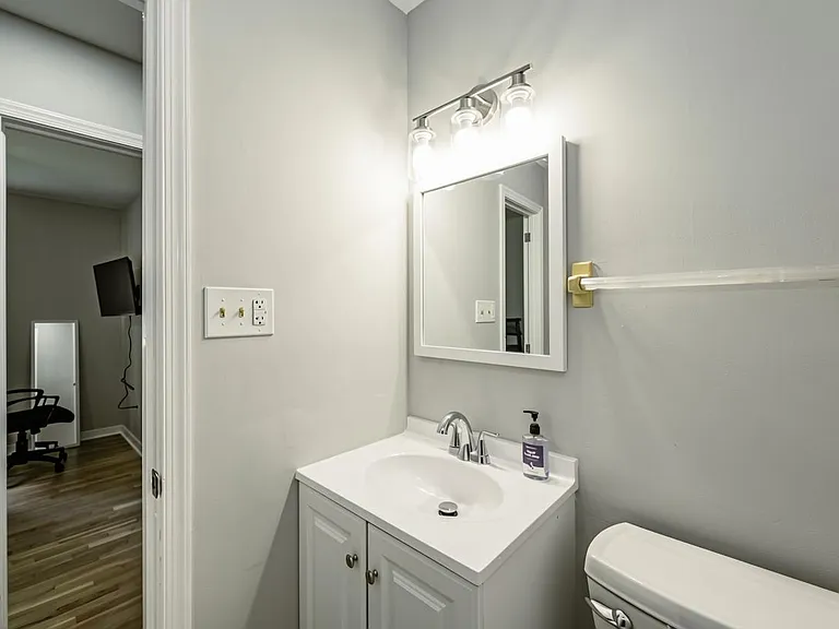 Bathroom features a single-sink vanity with storage, mirror lighting, and convenient towel bar placement.