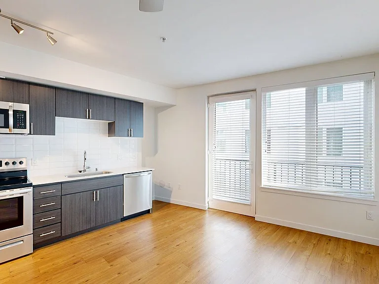 Apartment Kitchen with Stainless Steel Appliances, Dining and Living Room with Wood-Style Flooring.
