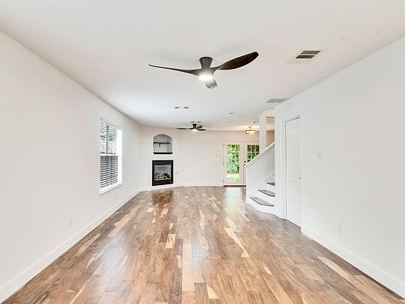 Open-concept living area with large windows, a cozy fireplace, elegant hardwood flooring, and new modern paint and light fixtures