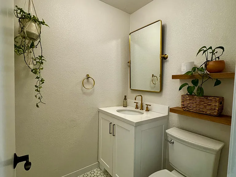 Beautifully remodeled guest powder room featuring a designer vanity, updated fixtures, custom tile flooring, floating wood shelves, and contemporary finishes. Conveniently located on the main level for guests and everyday use.