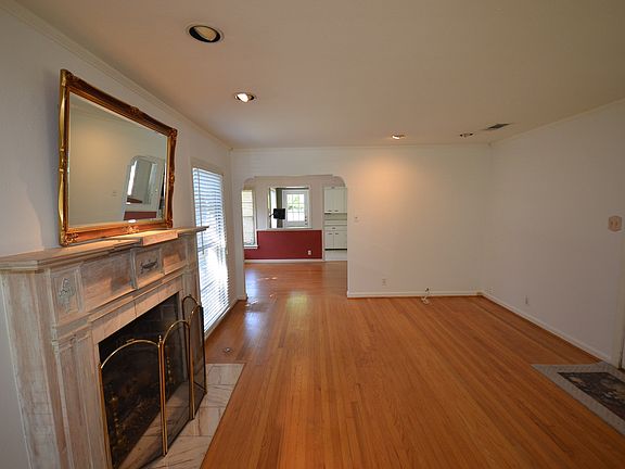 Living space featuring wood-finish flooring, a decorative fireplace with a mantel, recessed lighting, white interior walls, and an arched entry to an additional room