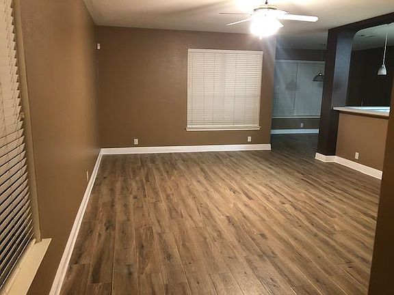 View of the living room from the front door. It has been freshly painted, has new wood look porcelain floor tiles and updated baseboards.You can see the dining room to the back right. You can also see the kitchen peninsula on the right.