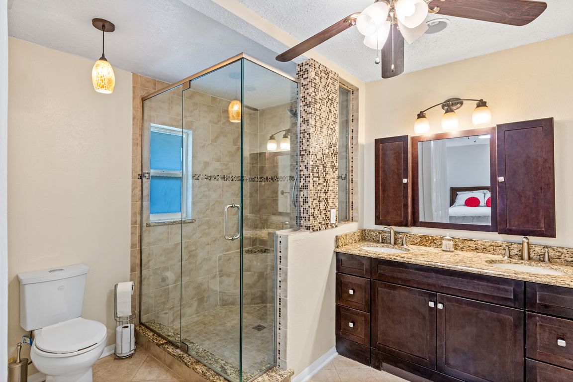 Upgraded primary ensuite bath with dual sink granite topped vanity and oversized seamless glass enclosed shower with built-in bench.