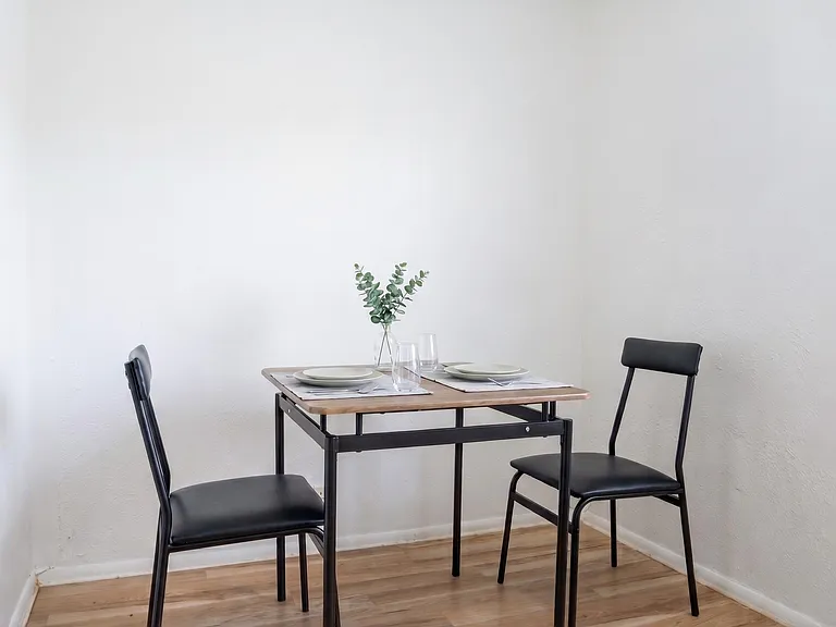 Compact dining nook with a two-seat table, durable flooring, and open wall space for additional storage or decor.