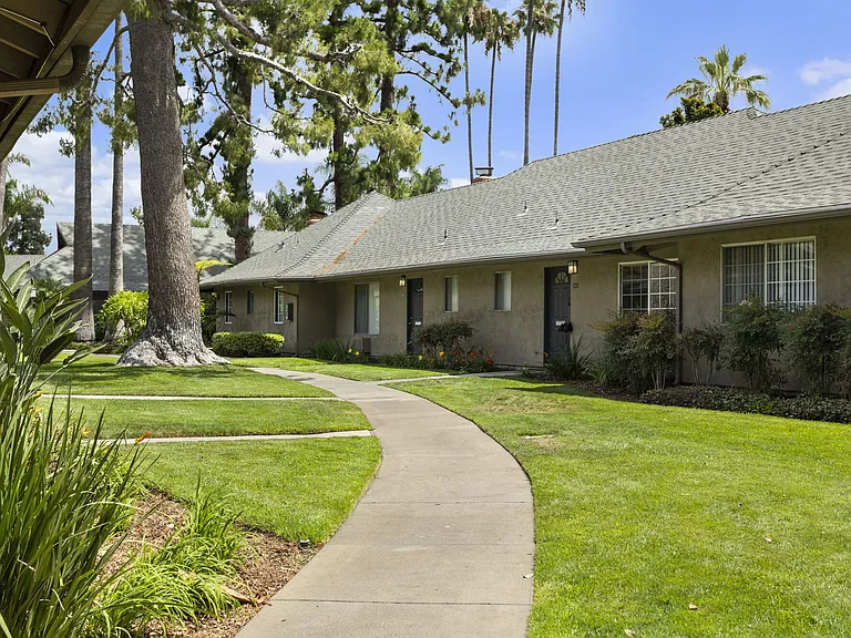 Walking paths through tropical landscaping at Mango Tree Apartments in Santa Ana, CA