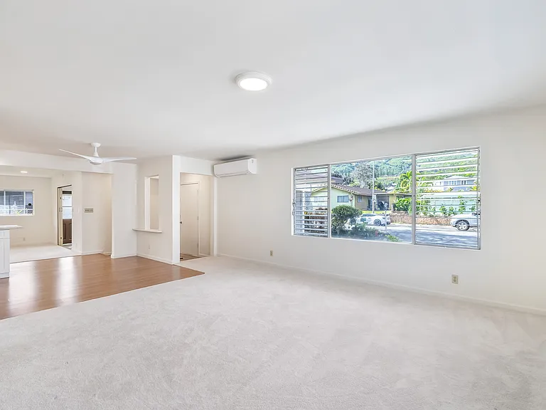 This shot of living room shows kitchen on left, front door to left of picture window. View of Ko'olaus (mountain) can be seen from this room.