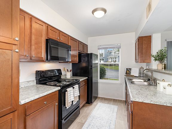A sleek kitchen featuring stylish black appliances and warm wooden cabinetry for a functional and inviting cooking space.