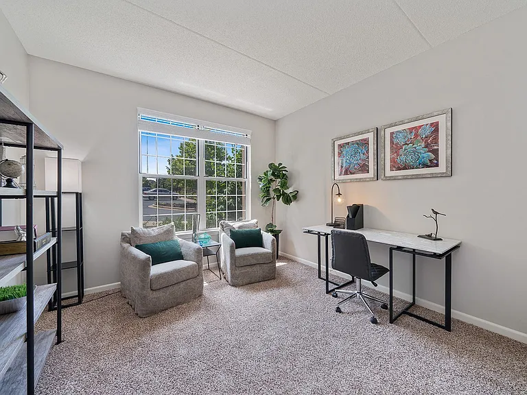 Carpeted office nook with large window and desk setup