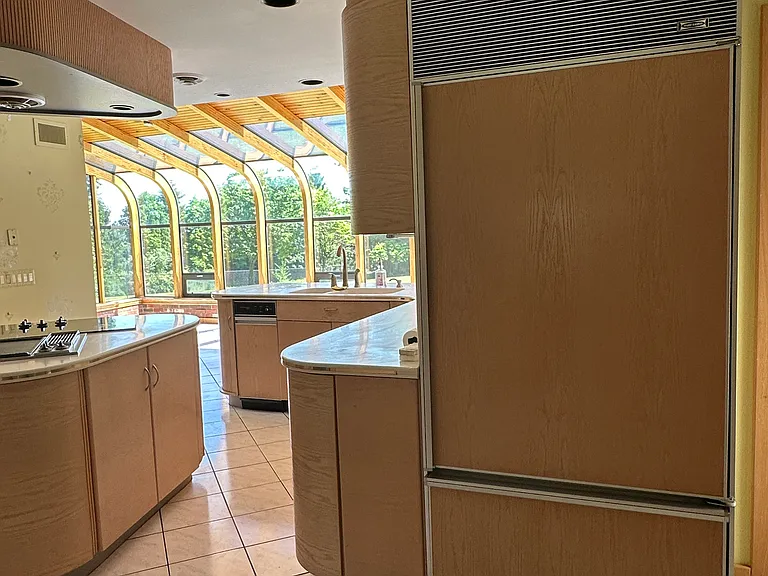Wide view of kitchen from front entrance, showing Sub Zero refrigerator with custom panels to match cabinets.