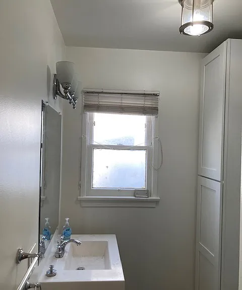Bathroom has various lighting with fan support. Cabinets in back provide added storage.