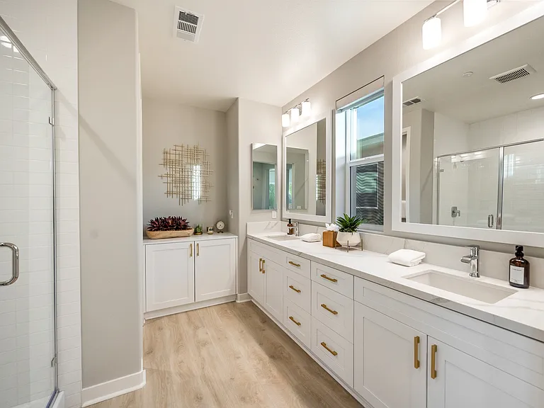 The master suite features a large step-in tile shower, his and hers vanity sinks, and a private restroom.