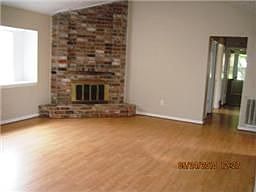 The den has laminate wood floors, a cathedral ceiling and a wood burning brick surround fireplace.