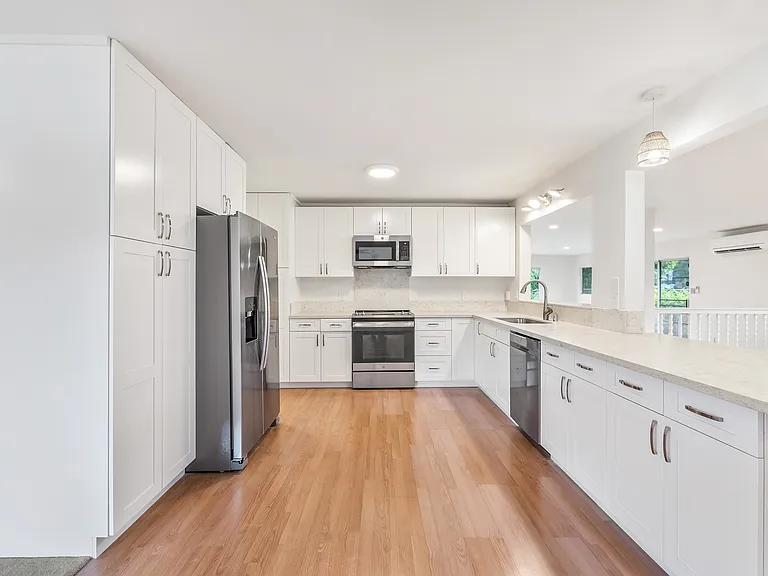 Another view of the kitchen. Newer refrigerator, stove, dishwasher, & microwave hood. Open and airy space with lots of counter space & cabinets.