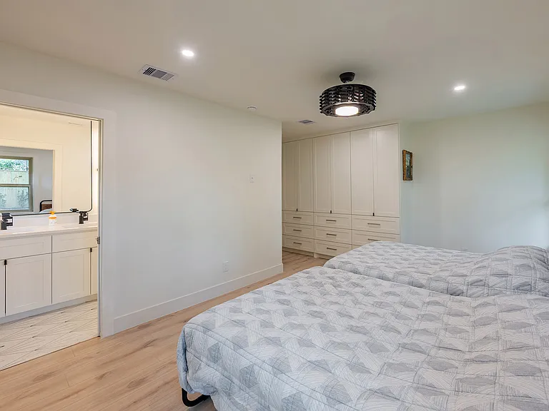 Comfortable bedroom with a flexible layout for seating or a workspace, featuring custom built-in storage and direct access to a beautifully updated ensuite bath.