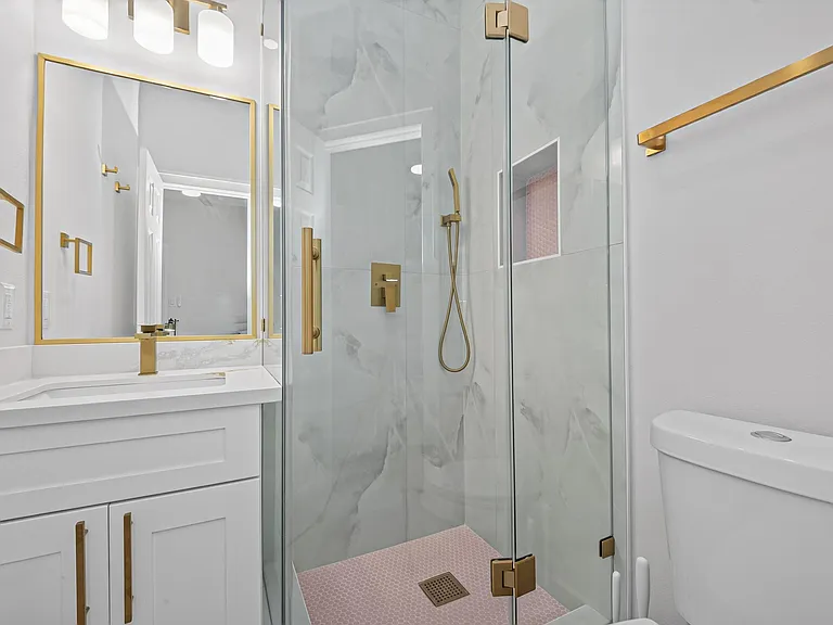 Updated bath with a glass-enclosed shower, marble-look tile, and a vanity with ample storage and framed mirror.