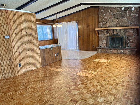 Great room and fireplace. Dining room on left. Wood parquet floor