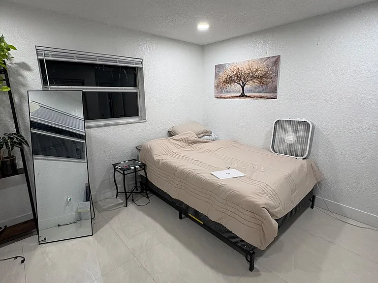 Private bedroom with tile floors, a window with blinds, and space for a bed plus a small desk or dresser.