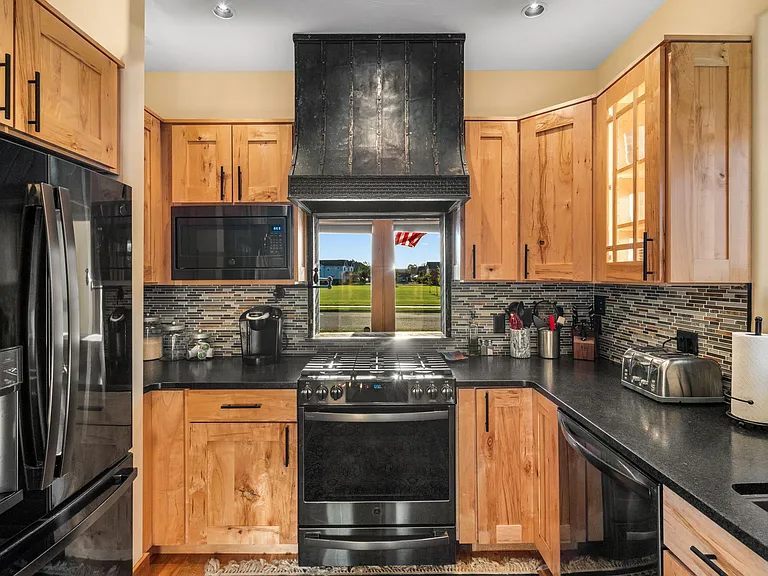 Black stainless Profile appliances, gas stove, and leathered quartz countertops.