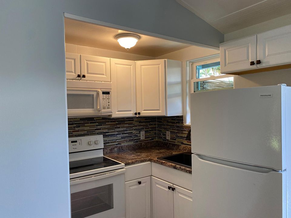 Kitchen with microwave oven, glass top stove, refrigerator, granite sink with stone back splash.