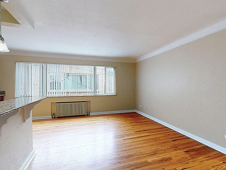 Bright and spacious living area with polished hardwood floors and a stylish breakfast bar, perfect for entertaining.