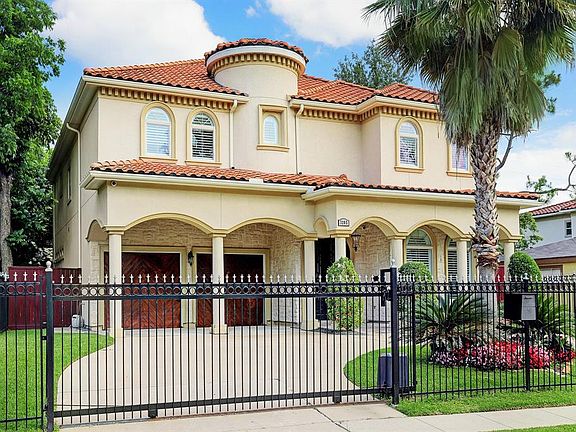 Mediterranean style home with a double car garage and fenced front yard.