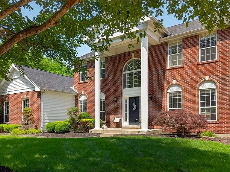 Traditional brick exterior featuring a prominent two-story portico with column supports, a large arched transom window above the main entry, and multiple multi-pane windows