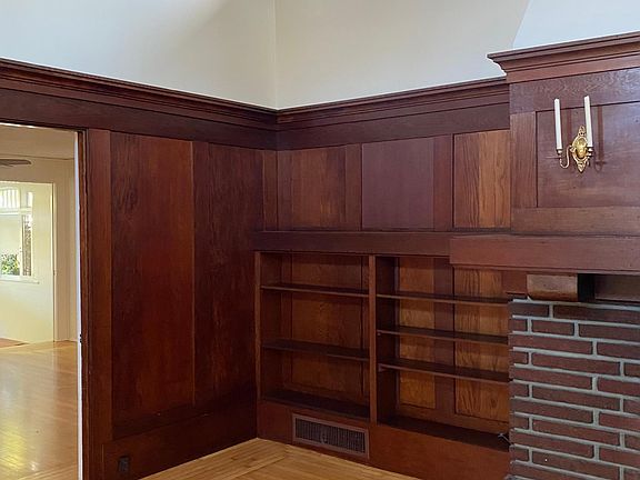Left side of fireplace next to bookshelves in main room.