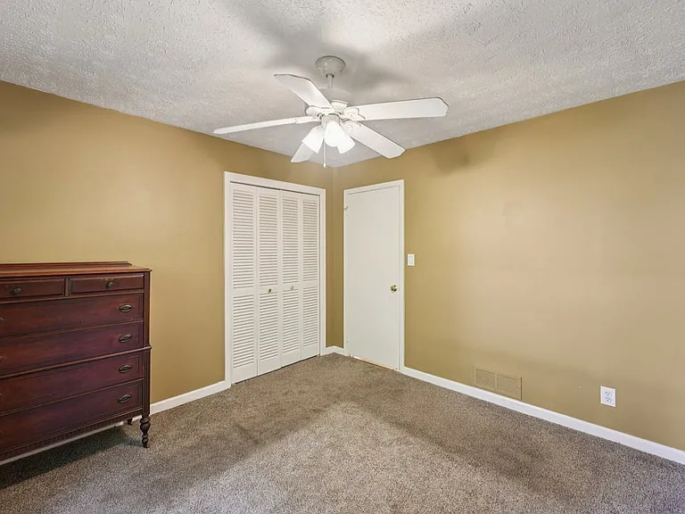 This cozy bedroom feels quietly enchanting, with natural light, a ceiling fan, and calming neutral warmth that invites relaxation, rest, and simple everyday comfort.
