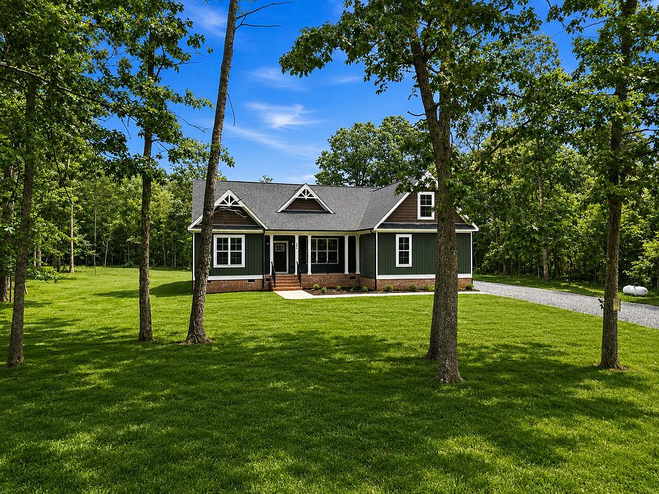 Nestled in Anna Coves, this single-story dark green house with white trim sits on a large grassy law