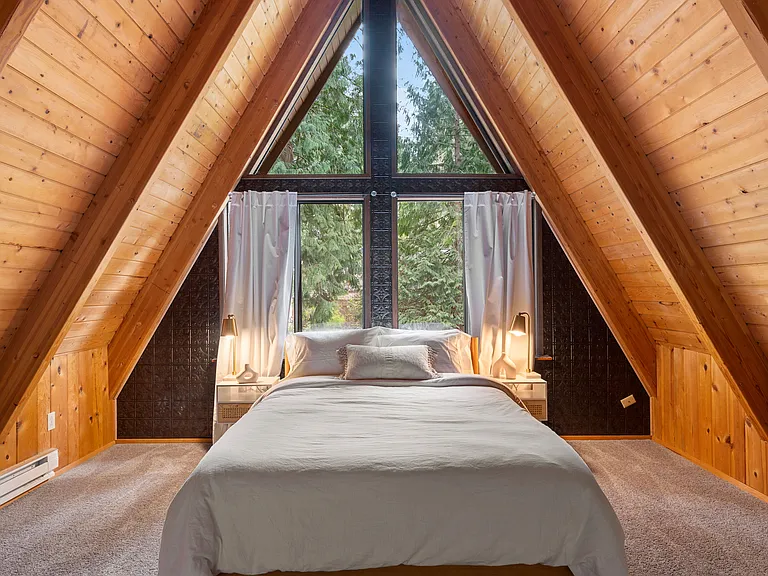 This second floor bedroom has two closets and room darkening curtains but the top triangular windows have no window coverings. No dresser is provided.