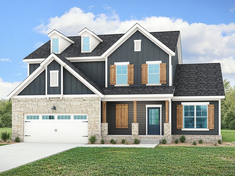 Elegant farmhouse with rustic wood shutters, sleek dark siding, and timeless stone accents in Brush