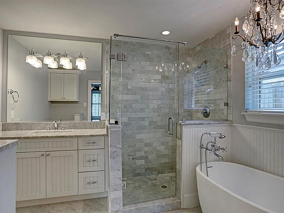 Marble tile in master bathroom and frameless glass shower.