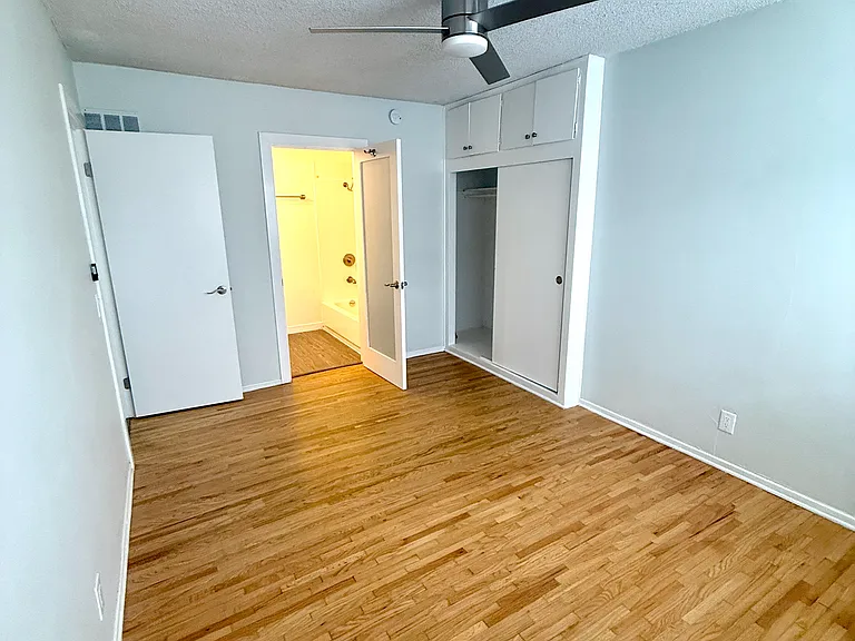 View of the bedroom, closet, bathroom and bedroom door from the opposite corner of the bedroom.