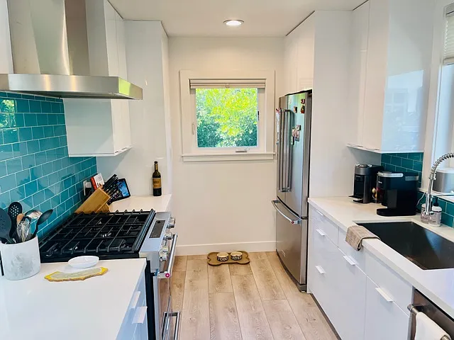 galley kitchen with glass tile and stainless appliances