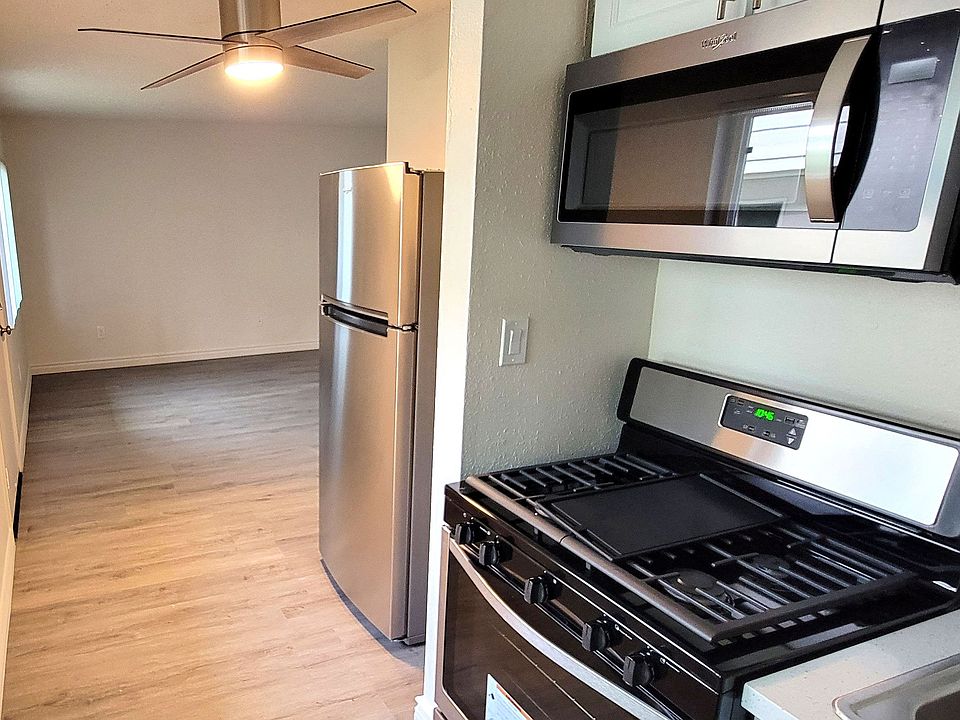 Kitchen with refrigerator, ceiling fan, gas range and microwave at Orlando Woods Apartments in El Cajon, California.