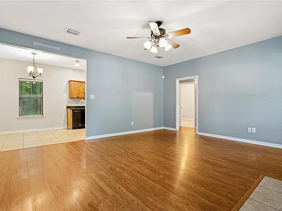 Unfurnished living room featuring light hardwood / wood-style flooring and ceiling fan with notable chandelier