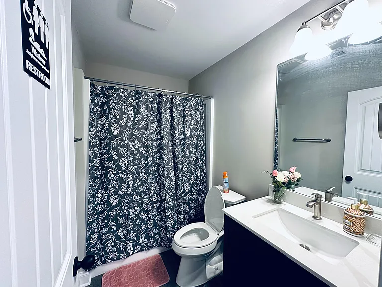 Full bathroom with tub/shower combo, large vanity with under-sink storage, and wide mirror with overhead lighting.